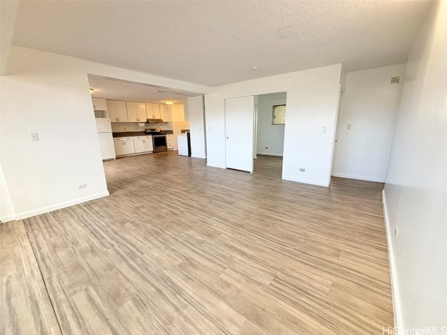 unfurnished living room featuring a textured ceiling and light wood-type flooring