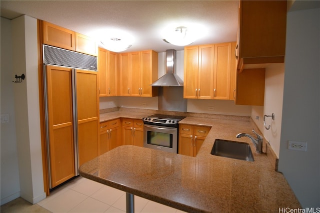 kitchen featuring paneled fridge, wall chimney range hood, kitchen peninsula, sink, and stainless steel electric range oven