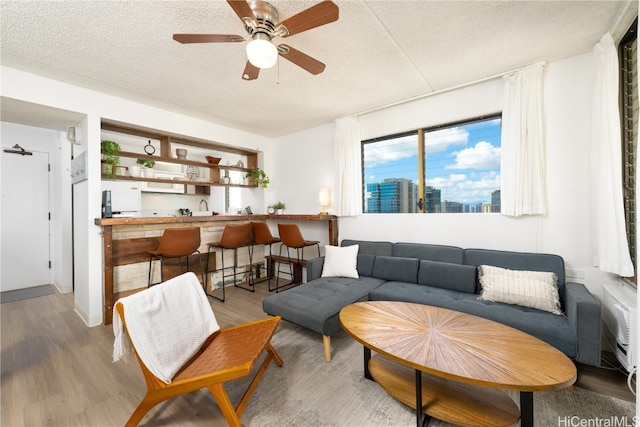 living room with a textured ceiling, light hardwood / wood-style floors, and ceiling fan