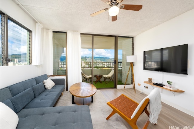 living room with expansive windows, a textured ceiling, wood-type flooring, and ceiling fan