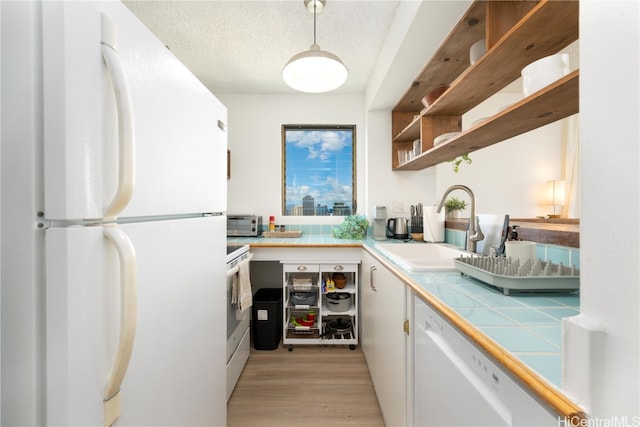 kitchen with tile countertops, light hardwood / wood-style flooring, white cabinets, a textured ceiling, and white appliances