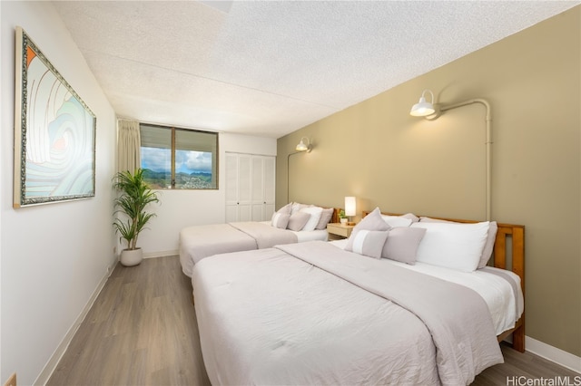 bedroom with a closet, hardwood / wood-style flooring, and a textured ceiling