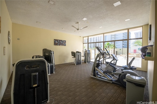 gym with ceiling fan, a textured ceiling, plenty of natural light, and dark carpet