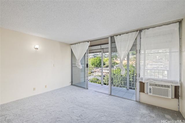 carpeted spare room with cooling unit, a textured ceiling, and a wall of windows