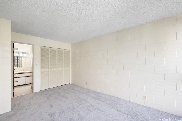 unfurnished bedroom featuring a textured ceiling, light colored carpet, and connected bathroom