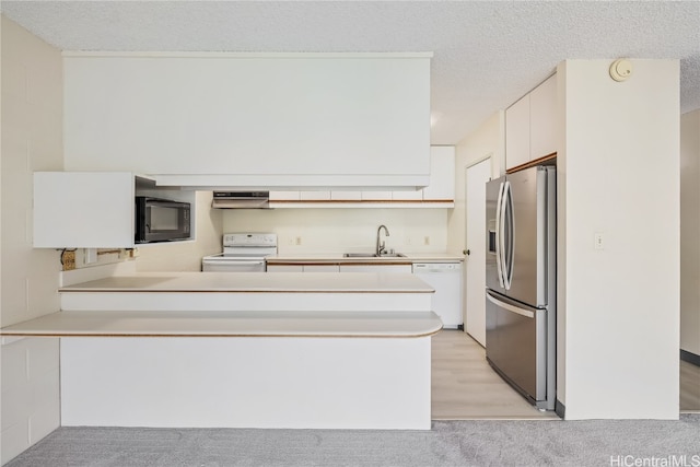 kitchen featuring white appliances, sink, kitchen peninsula, white cabinetry, and extractor fan