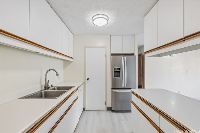 kitchen with sink, stainless steel fridge with ice dispenser, light wood-type flooring, white cabinets, and a textured ceiling