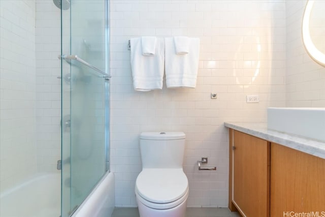 full bathroom with vanity, toilet, tile walls, and enclosed tub / shower combo