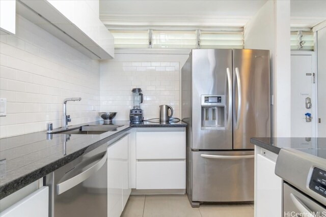 kitchen with tasteful backsplash, light tile patterned floors, appliances with stainless steel finishes, white cabinetry, and sink