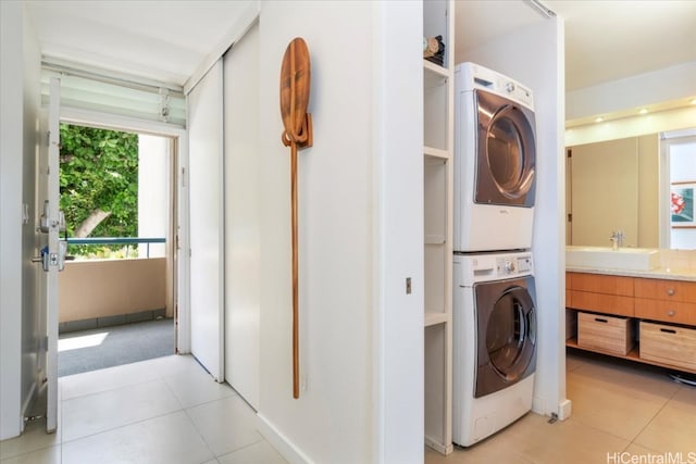 clothes washing area with sink, stacked washer and clothes dryer, and light tile patterned floors