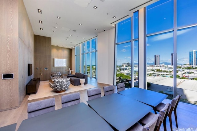 dining area with a wall of windows, a view of city, and wood finished floors