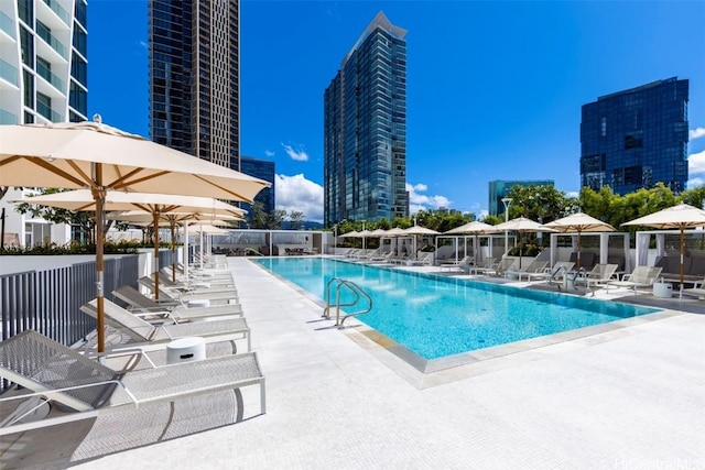 pool with a patio area, a view of city, and fence