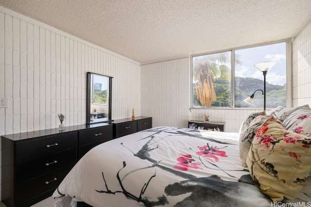 bedroom with a mountain view, a textured ceiling, and tile walls