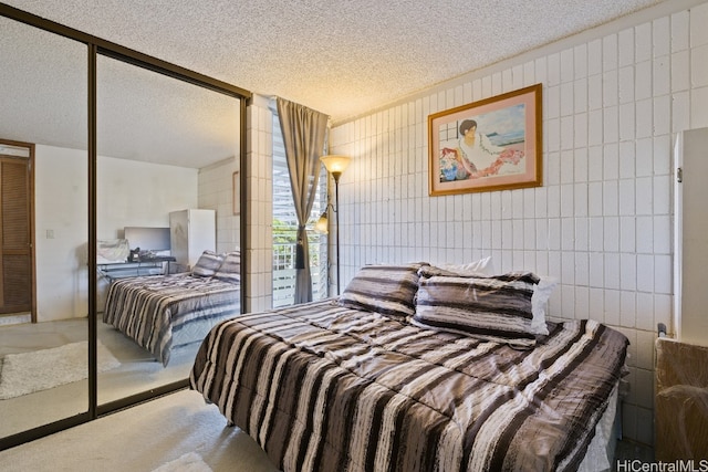 carpeted bedroom featuring a closet, a textured ceiling, and tile walls