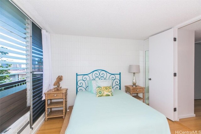 bedroom with a textured ceiling and light hardwood / wood-style flooring