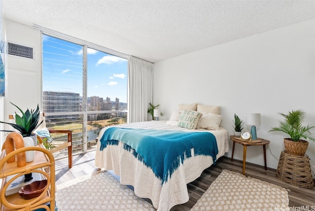 bedroom featuring hardwood / wood-style floors, a wall of windows, and a textured ceiling