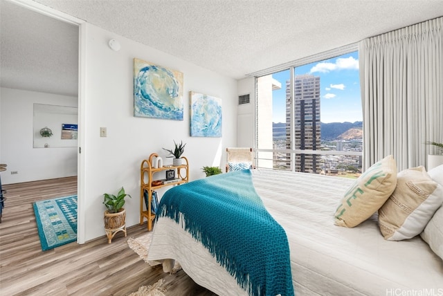 bedroom featuring expansive windows, a textured ceiling, and hardwood / wood-style flooring