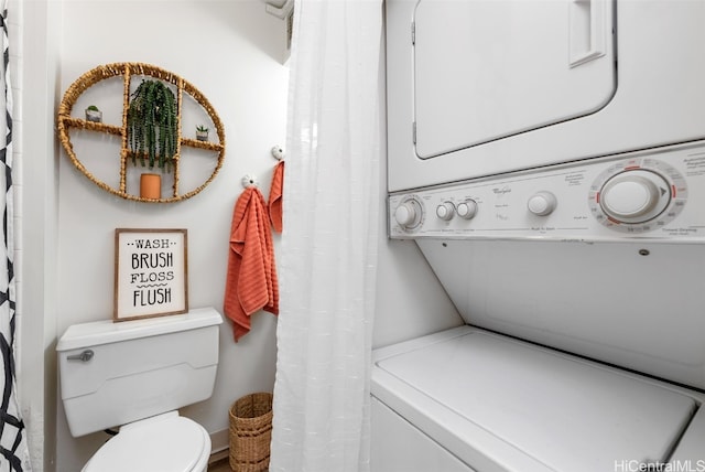 bathroom featuring stacked washer / dryer and toilet