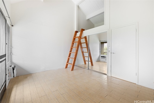 unfurnished room featuring beamed ceiling, light hardwood / wood-style floors, and high vaulted ceiling