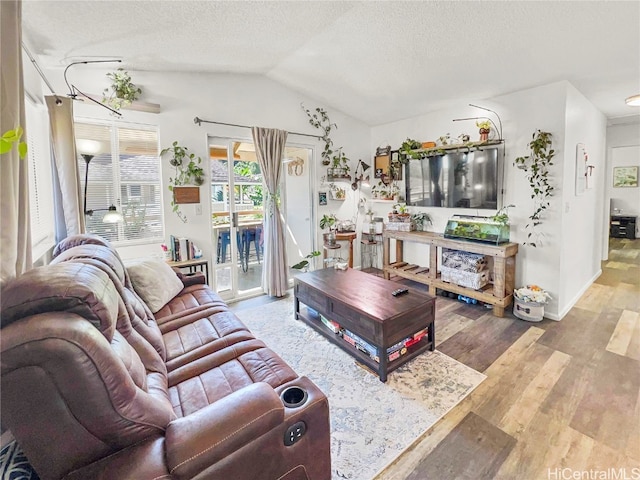 living room with a textured ceiling, light wood-type flooring, and vaulted ceiling