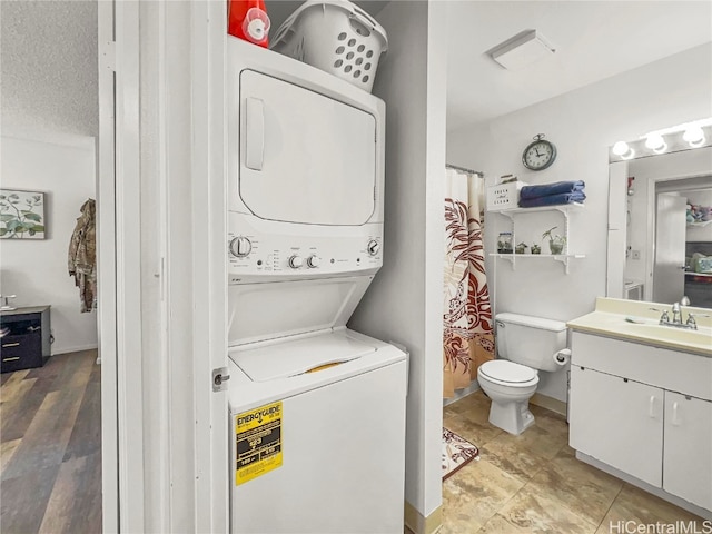 clothes washing area featuring a textured ceiling, light hardwood / wood-style floors, sink, and stacked washer and clothes dryer