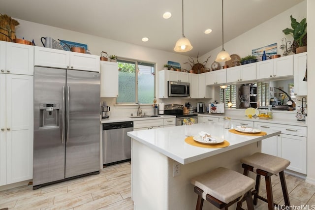 kitchen with sink, hanging light fixtures, white cabinetry, stainless steel appliances, and a breakfast bar