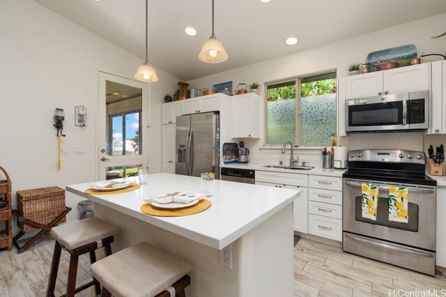 kitchen featuring stainless steel appliances, sink, pendant lighting, and white cabinets