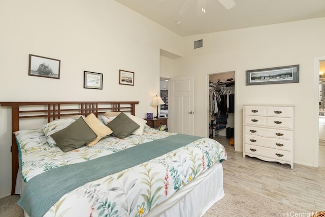 bedroom with a closet, a walk in closet, ensuite bath, light hardwood / wood-style floors, and ceiling fan