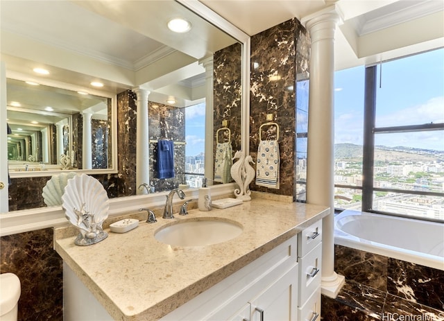 bathroom with vanity, crown molding, decorative columns, and tiled tub