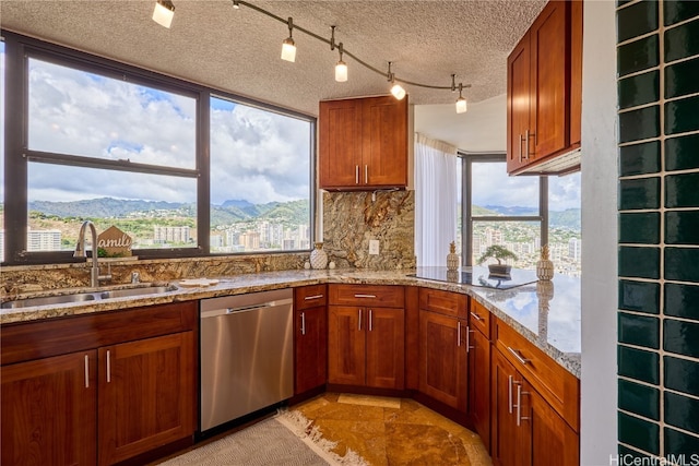 kitchen featuring a textured ceiling, light stone countertops, stainless steel dishwasher, a mountain view, and sink