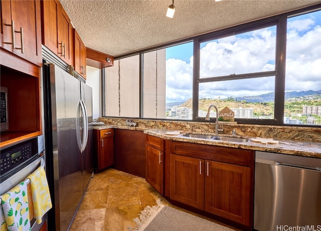 kitchen with sink, light stone countertops, stainless steel appliances, and a textured ceiling