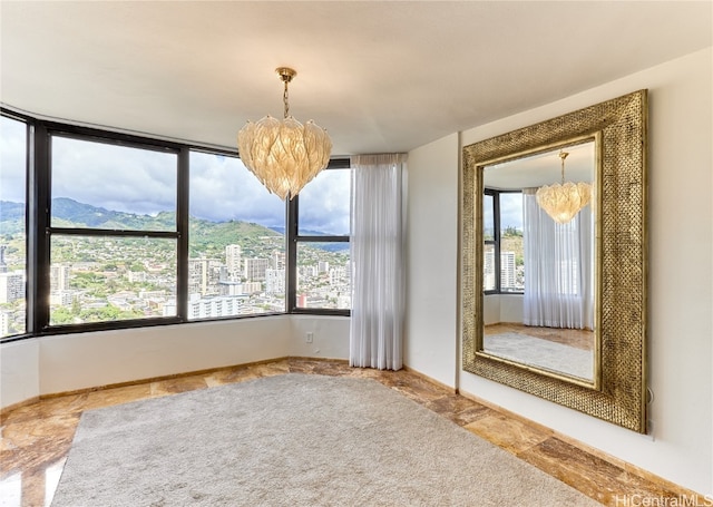 empty room with a mountain view, a wealth of natural light, and a chandelier