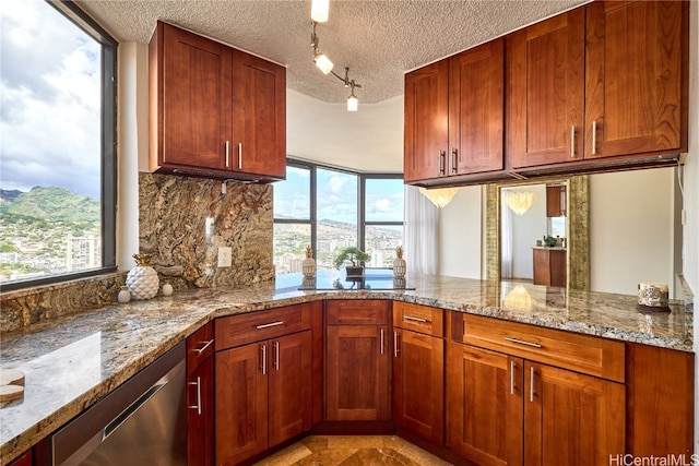 kitchen featuring tasteful backsplash, a textured ceiling, kitchen peninsula, light stone counters, and a mountain view