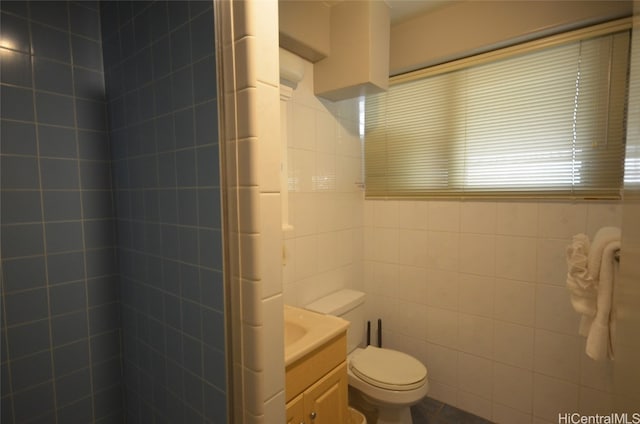 bathroom with vanity, toilet, and tile walls