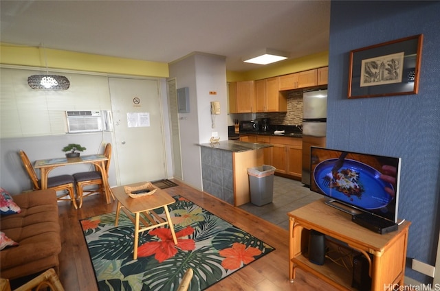 kitchen featuring pendant lighting, light wood-type flooring, tasteful backsplash, light brown cabinetry, and stainless steel refrigerator