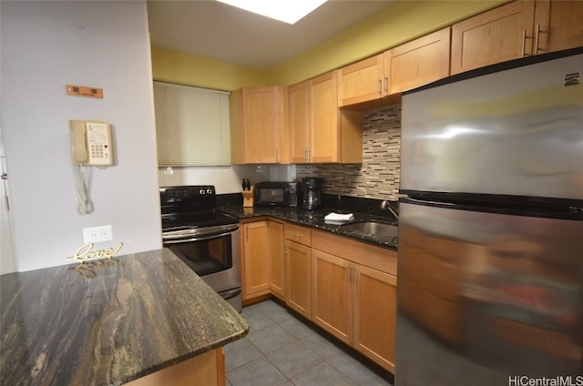 kitchen with appliances with stainless steel finishes, decorative backsplash, dark stone countertops, and sink