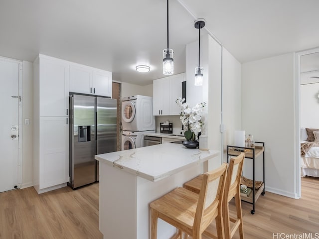 kitchen featuring light hardwood / wood-style floors, kitchen peninsula, stainless steel fridge, and stacked washing maching and dryer