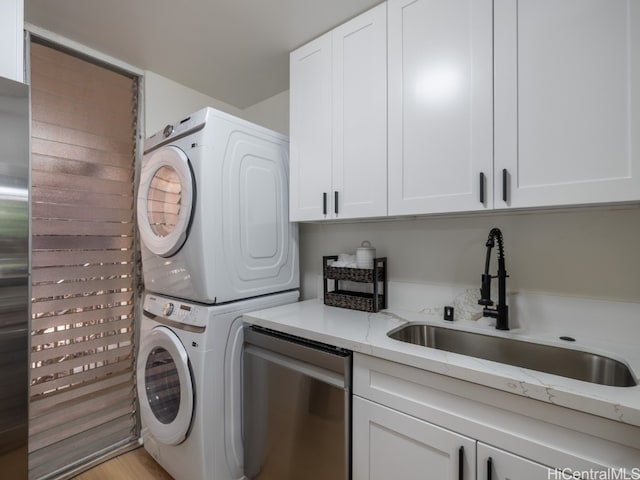 washroom with sink, light hardwood / wood-style flooring, cabinets, and stacked washer and dryer