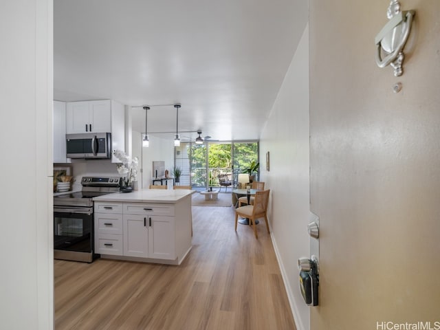 kitchen featuring white cabinetry, hanging light fixtures, stainless steel appliances, and light wood-type flooring