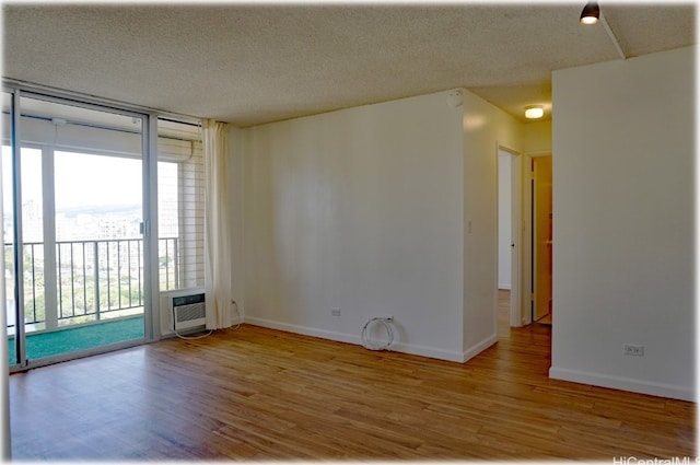 unfurnished room with a textured ceiling, light hardwood / wood-style floors, and a wall mounted AC