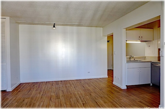 interior space featuring dishwasher, a textured ceiling, light hardwood / wood-style flooring, and sink