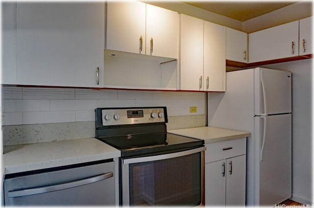 kitchen featuring decorative backsplash, white refrigerator, white cabinetry, stainless steel range with electric cooktop, and range hood