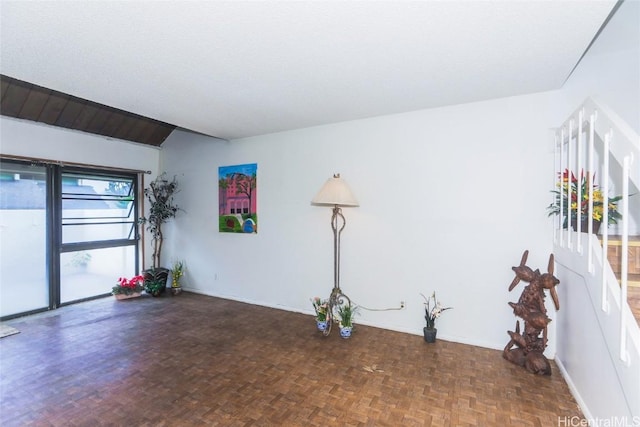 unfurnished room featuring a textured ceiling, parquet floors, and lofted ceiling