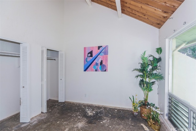 unfurnished bedroom featuring beam ceiling, high vaulted ceiling, and two closets