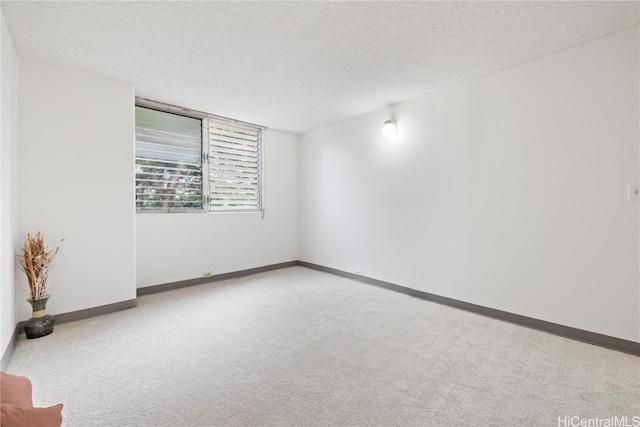 spare room with carpet flooring, baseboards, and a textured ceiling