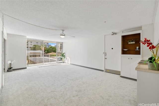 interior space featuring baseboards, carpet flooring, a textured ceiling, and a ceiling fan