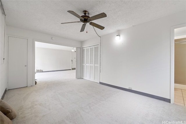 empty room featuring baseboards, carpet floors, a textured ceiling, and a ceiling fan