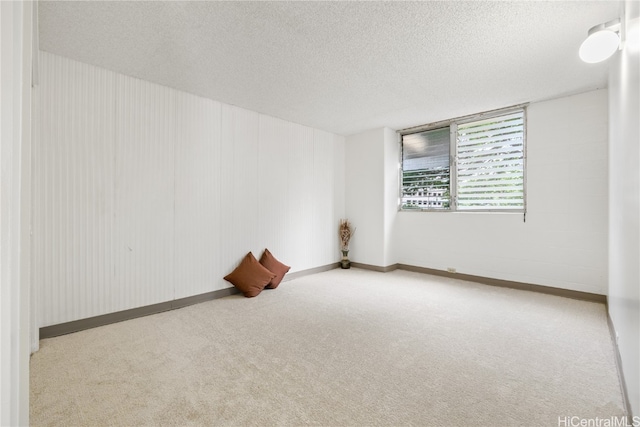 spare room featuring carpet flooring, a textured ceiling, and baseboards