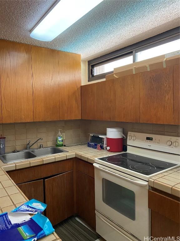 kitchen featuring tile counters, white range with electric stovetop, sink, and tasteful backsplash