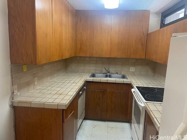1088 Bishop St Unit 1213, Honolulu, HI 96813 - kitchen with white appliances, a sink, tasteful backsplash, brown cabinetry, and tile countertops